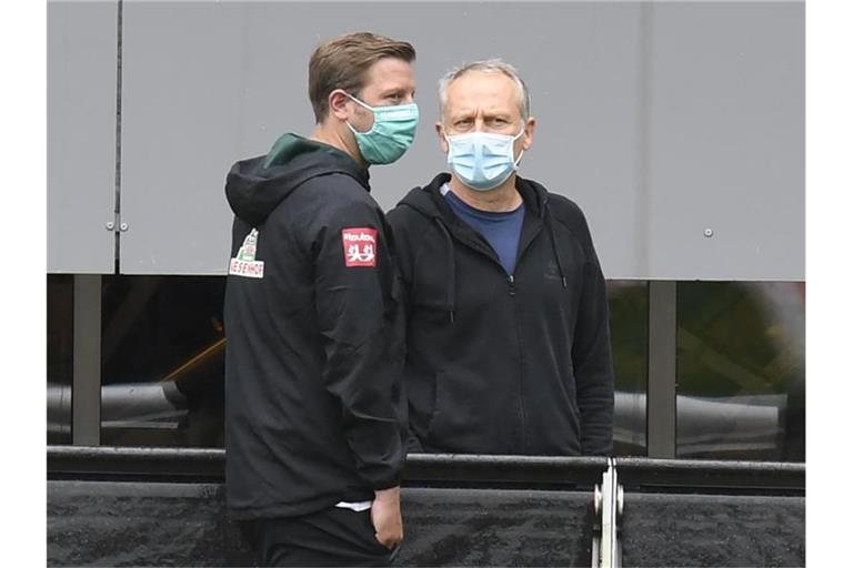 Christian Streich (r) und Florian Kohfeldt unterhalten sich. Foto: Thomas Kienzle/AFP-Pool/dpa/Archivbild