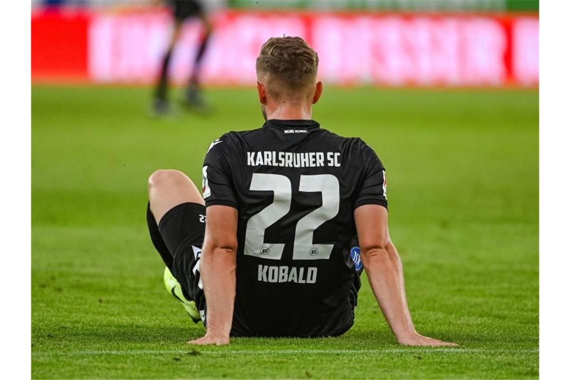 Christoph Kobald sitzt nach dem mit 2:1 verlorenen Spiel gegen Regensburg enttäuscht auf dem Rasen. Foto: Armin Weigel/dpa