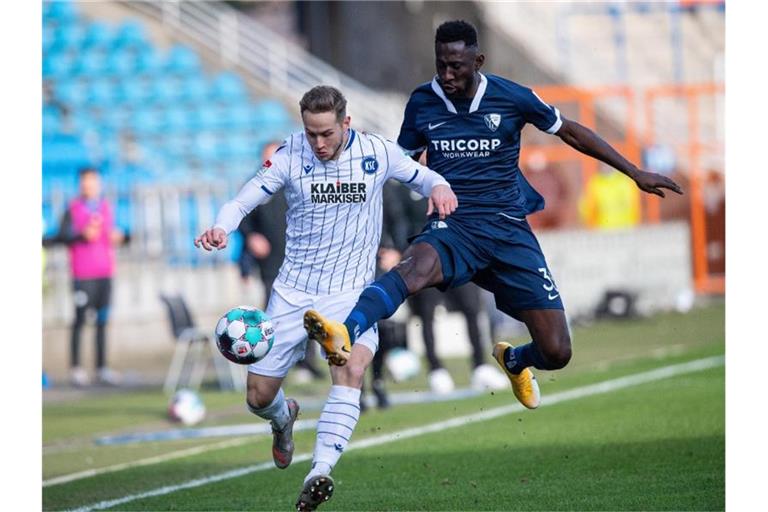 Christoph Kobald vom Karlsruher SC (l) und Bochums Silvere Ganvoula kämpfen um den Ball. Foto: Guido Kirchner/dpa