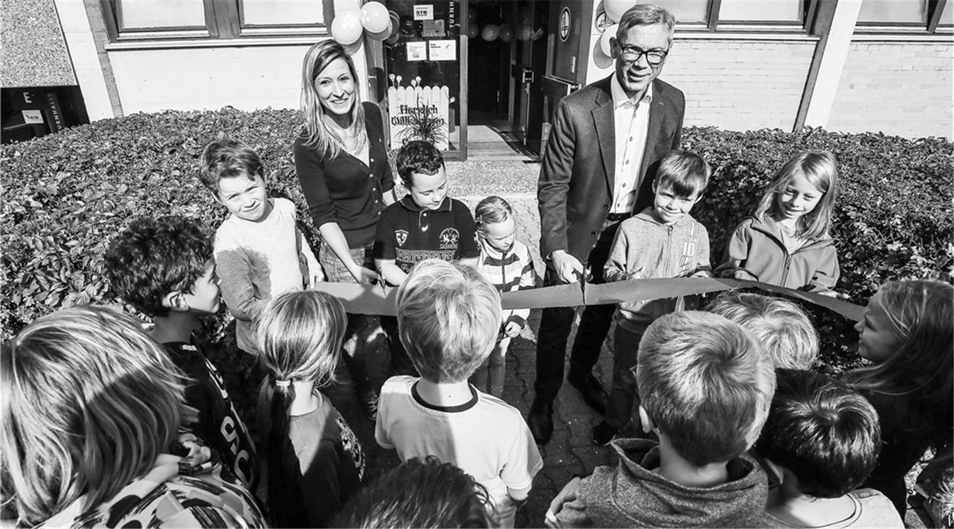 Claudia Lächele, Leiterin des Horts und Bürgermeister Hansjörg Weinbrenner durchschneiden bei der offiziellen Eröffnung das Band, anschließend geht es mit einer Polonaise durch das Gebäude. Foto: A. Becher