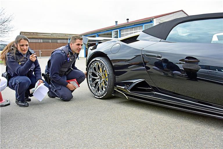 Corinne Peterolff und Oliver Schäfer kontrollieren einen schwarzen Lamborghini. Foto: Tobias Sellmaier