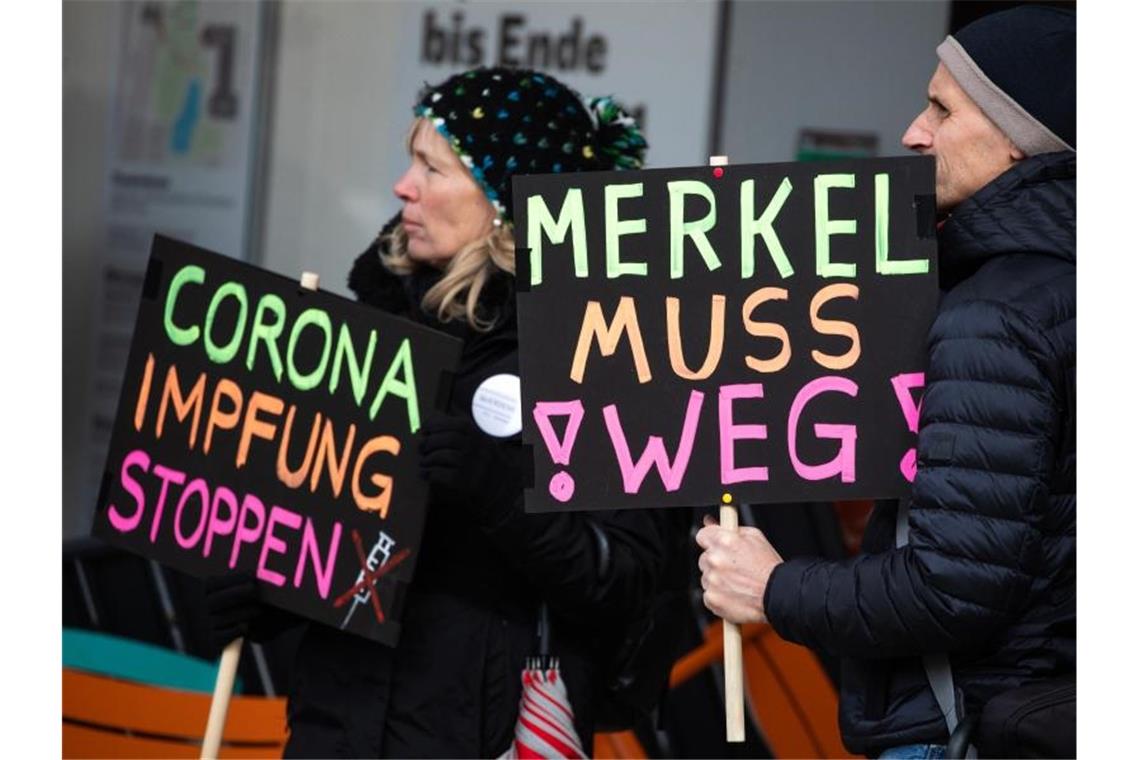 "„Corona-Impfung stoppen“" und „"Merkel muss weg“" steht auf Schildern zweier Teilnehmer einer Demonstration in der Stuttgarter Innenstadt. Foto: Christoph Schmidt/dpa/Archivbild