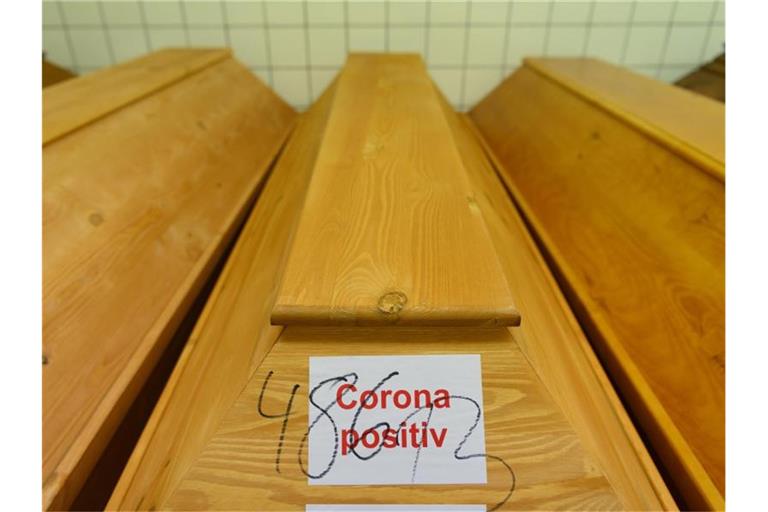 „Corona positiv“ steht auf einem Sarg mit einem Verstorbenen, der an oder mit dem Coronavirus gestorben ist. Foto: Robert Michael/dpa-Zentralbild/dpa
