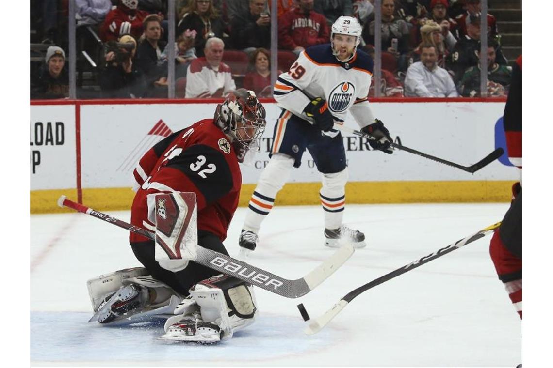 Coyotes-Torwart Antti Raanta (l) stoppt einen Schuss Leon Draisaitls (M) von den Edmonton Oilers. Foto: Ross D. Franklin/AP/dpa
