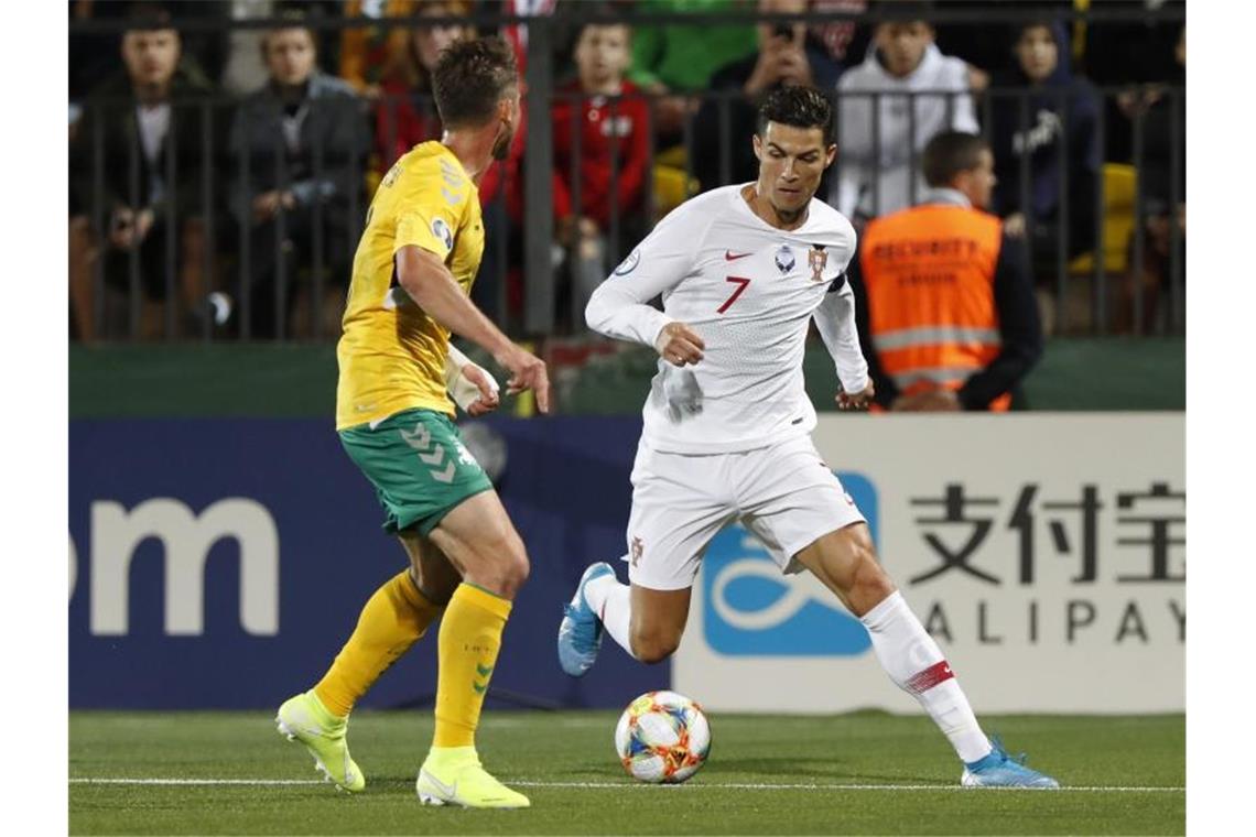 Cristiano Ronaldo (r) im Duell mit dem Litauer Saulius Mikoliunas. Foto: Mindaugas Kulbis/AP