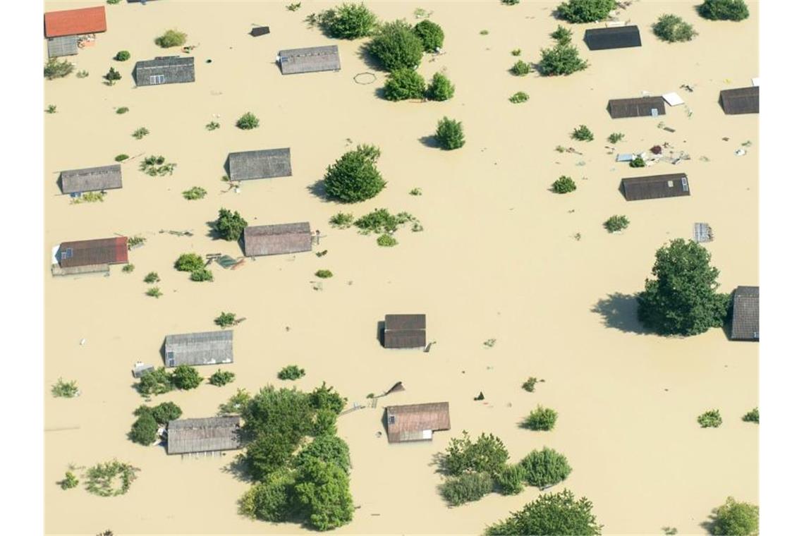 Dächer ragen im Juni 2013 nahe Deggendorf (Bayern) nach einem Dammbruch aus dem Hochwasser der Donau. Foto: Armin Weigel/dpa