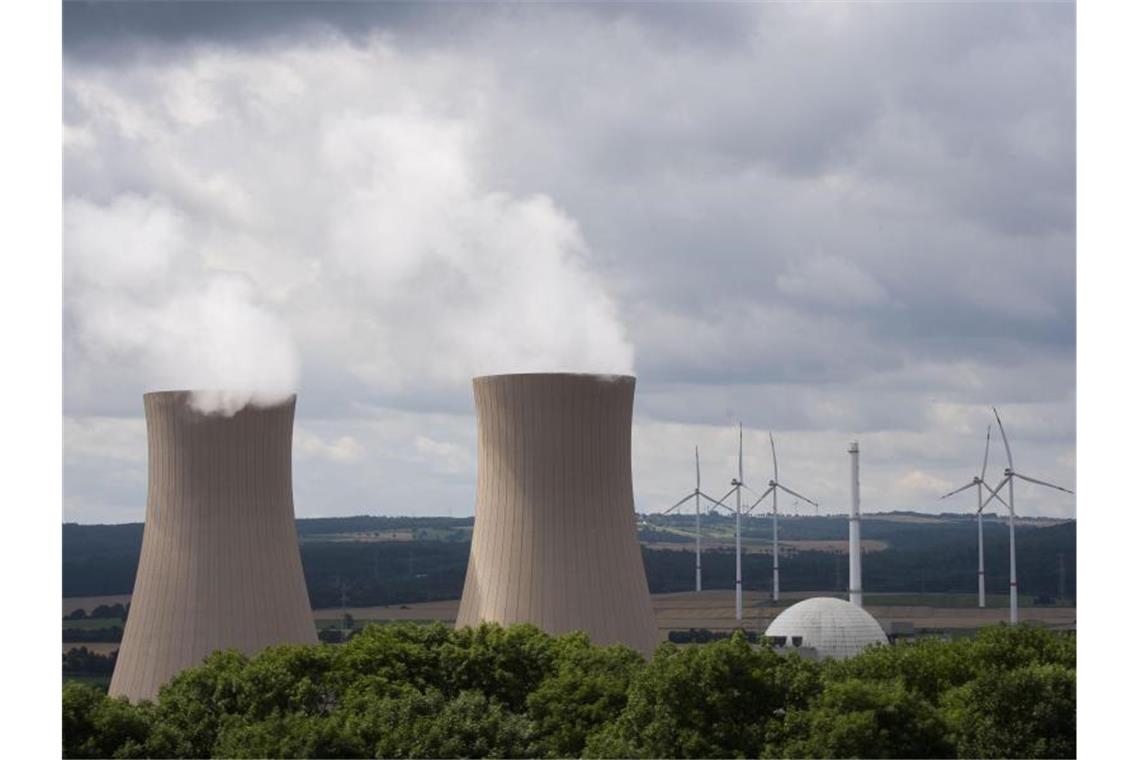 Dampf steigt aus den Kühltürmen eines Atomkraftwerks. Im Hintergrund sind Windräder zu sehen. Foto: Julian Stratenschulte/dpa
