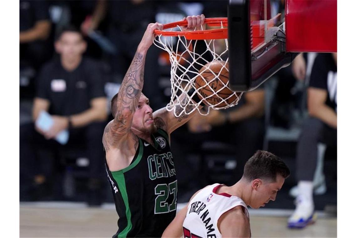 Daniel Theis (l) von den Boston Celtics hängt nach einem Dunking am Korb. Foto: Mark J. Terrill/AP/dpa