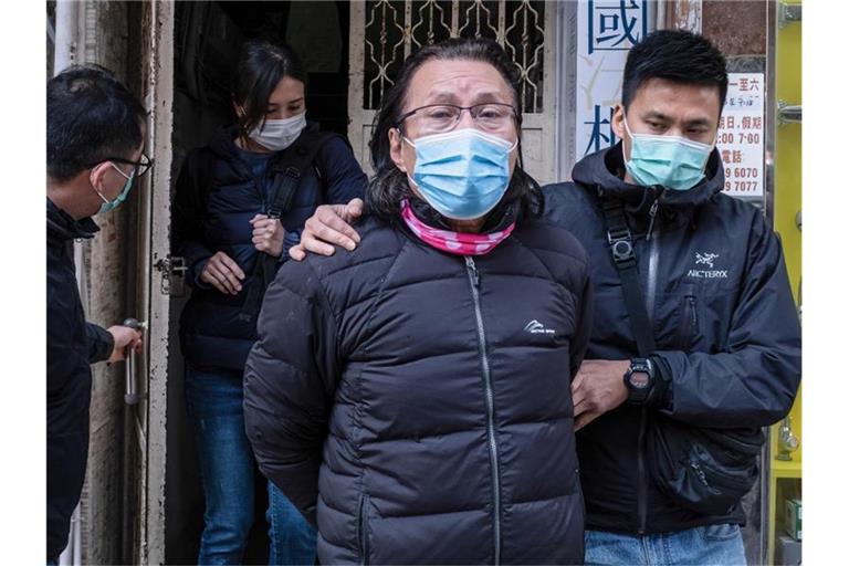 Daniel Wong Kwok-tung (l), Bezirksrat und Anwalt aus dem Stadtteil Kowloon in Hongkong, wird von Polizisten aus seinem Büro eskortiert. Foto: Isaac Wong/SOPA Images via ZUMA Wire/dpa