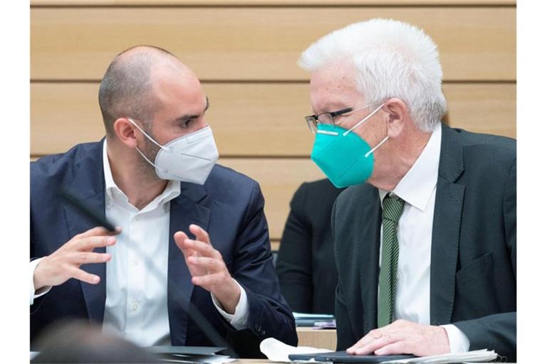 Danyal Bayaz (l) und Winfried Kretschmann sprechen miteinander. Foto: Marijan Murat/dpa