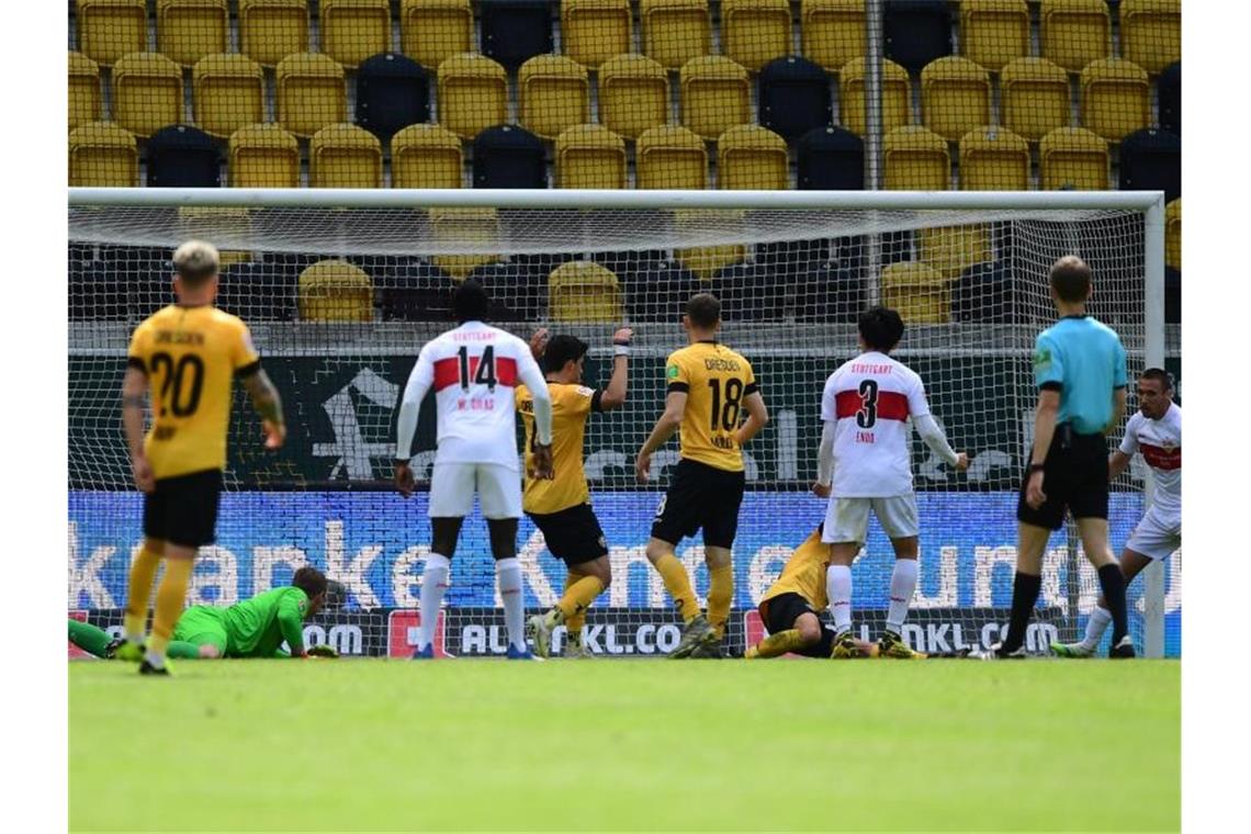 Darko Churlinov (r.) von Stuttgart erzielt das 0:2 gegen Torwart Kevin Broll (2.v.l) von Dresden. Foto: Robert Michael/dpa-Pool/dpa