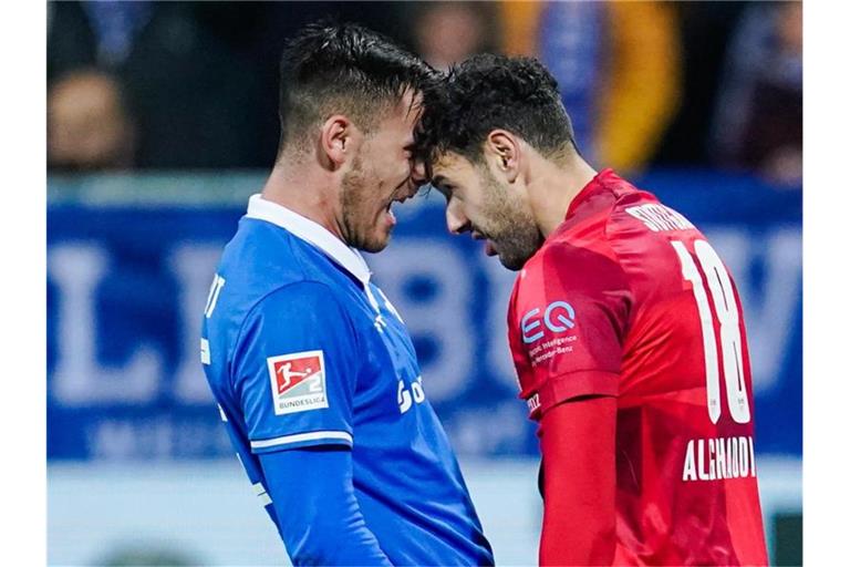 Darmstadts Dario Dumic (l) und Stuttgarts Hamadi Al Ghaddioui geraten während des Spiels aneinander. Foto: Uwe Anspach/dpa