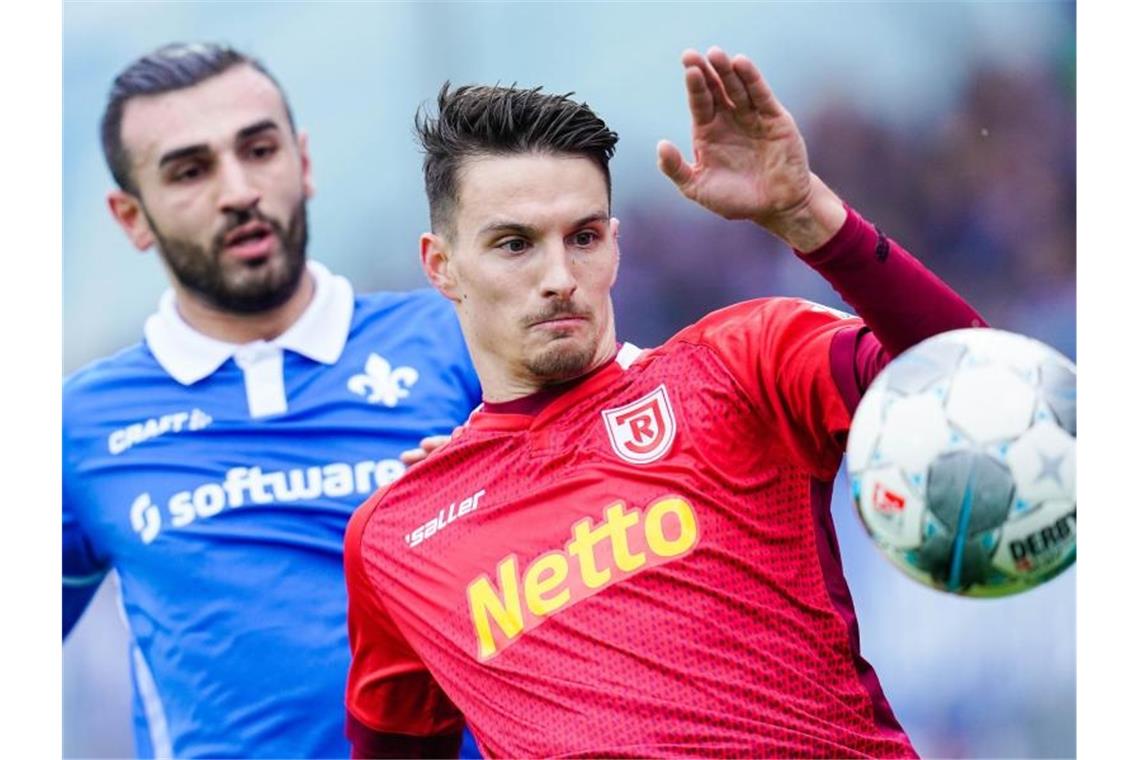 Darmstadts Serdar Dursun (l) und Regensburgs Sebastian Stolze kämpfen um den Ball. Foto: Uwe Anspach/dpa