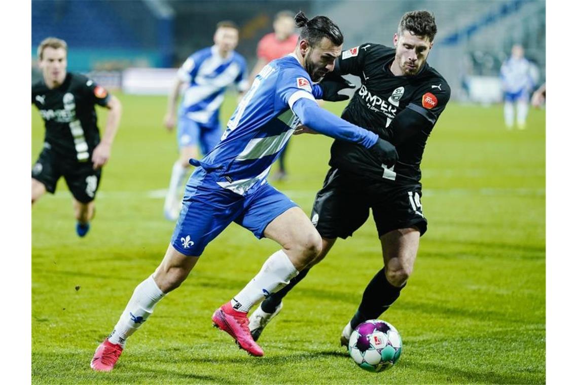 Darmstadts Serdar Dursun (l) und Sandhausens Tim Kister kämpfen um den Ball. Foto: Uwe Anspach/dpa