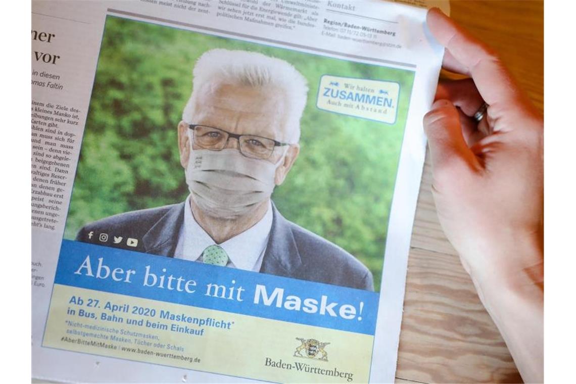 Kretschmann wirbt für die Maske: Land will mehr testen Das Abbild von Ministerpräsident Kretschmann mit Mundschutz ist in der Stuttgarter Zeitung zu sehen. Foto: Christoph Schmidt/dpa