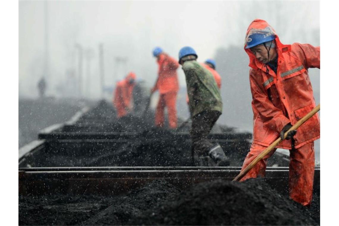 Das Archivbild zeigt Arbeiter auf einem mit Kohle beladenen Zug. China fördert weiter Kohle für seinen Energiebedarf - die Gruben gelten jedoch als sehr anfällig für Unglücke. Foto: Hu Guolin/epa/dpa