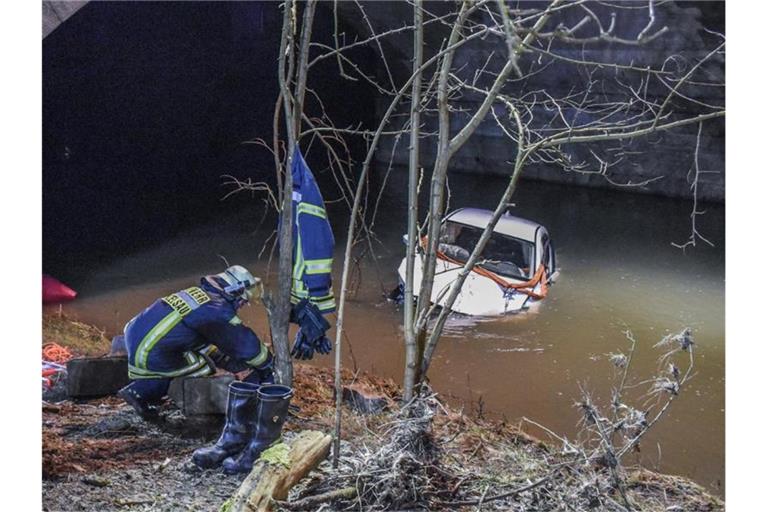 Das Auto liegt unterhalb der Brücke am Fluss Kocher in Künzelsau. Foto: Fabian Koss/onw-images/dpa
