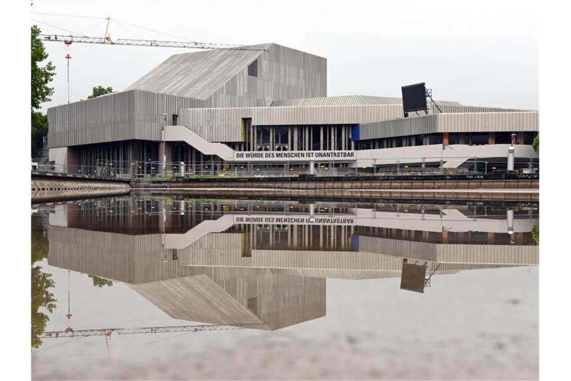 Das Badische Staatstheater spiegelt sich in einer Wasserfläche. Foto: Uli Deck/dpa/Archivbild