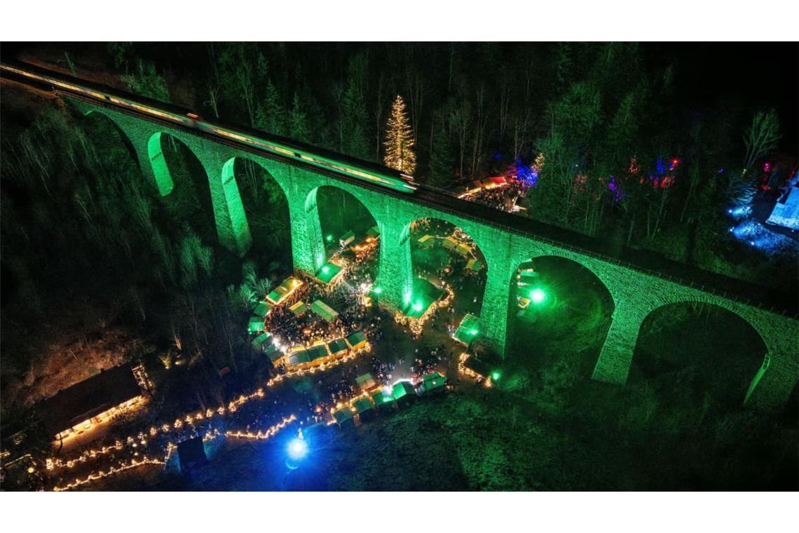 Das beleuchtete Eisenbahn-Viadukt der Höllentalbahn verläuft über dem Weihnachtsmarkt in der Ravennaschlucht. Viele Besucher kommen extra für den Weihnachtsmarkt in den Schwarzwald.