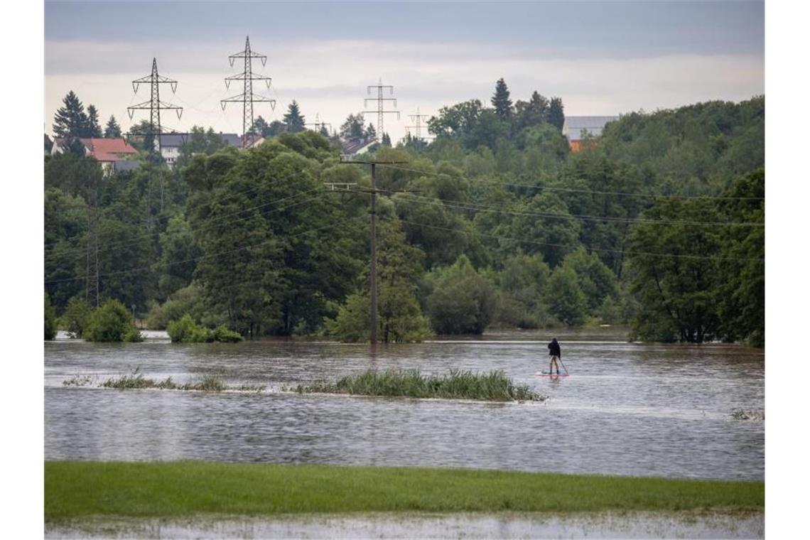 Das beste draus machen: Dieser Mann gleitet auf seinem Stand-Up-Paddle auf der über die Ufer getretene Zenn im bayrischen Lohe. Foto: Daniel Karmann/dpa