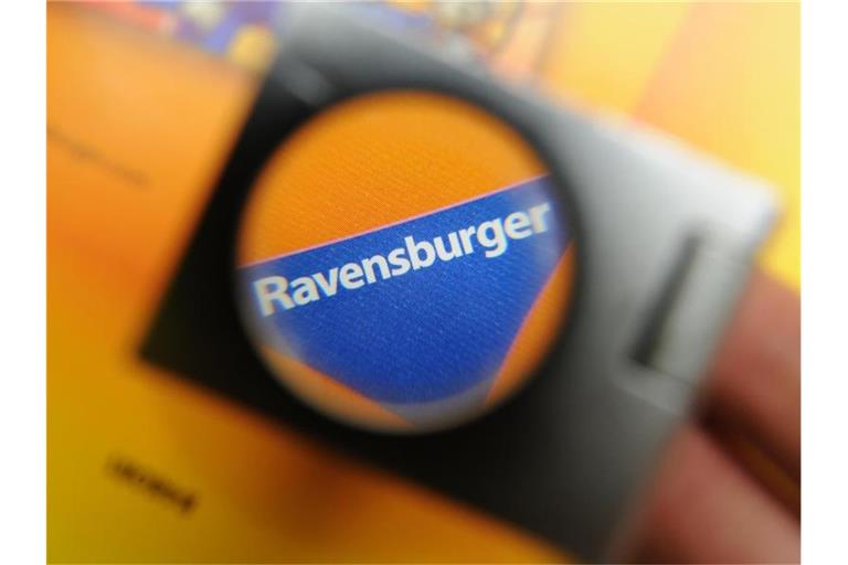 Das blaue Dreiecks-Logo ist beim Spielehersteller Ravensburger AG in Ravensburg durch eine Lupe zu sehen. Foto: Felix Kästle/Archiv