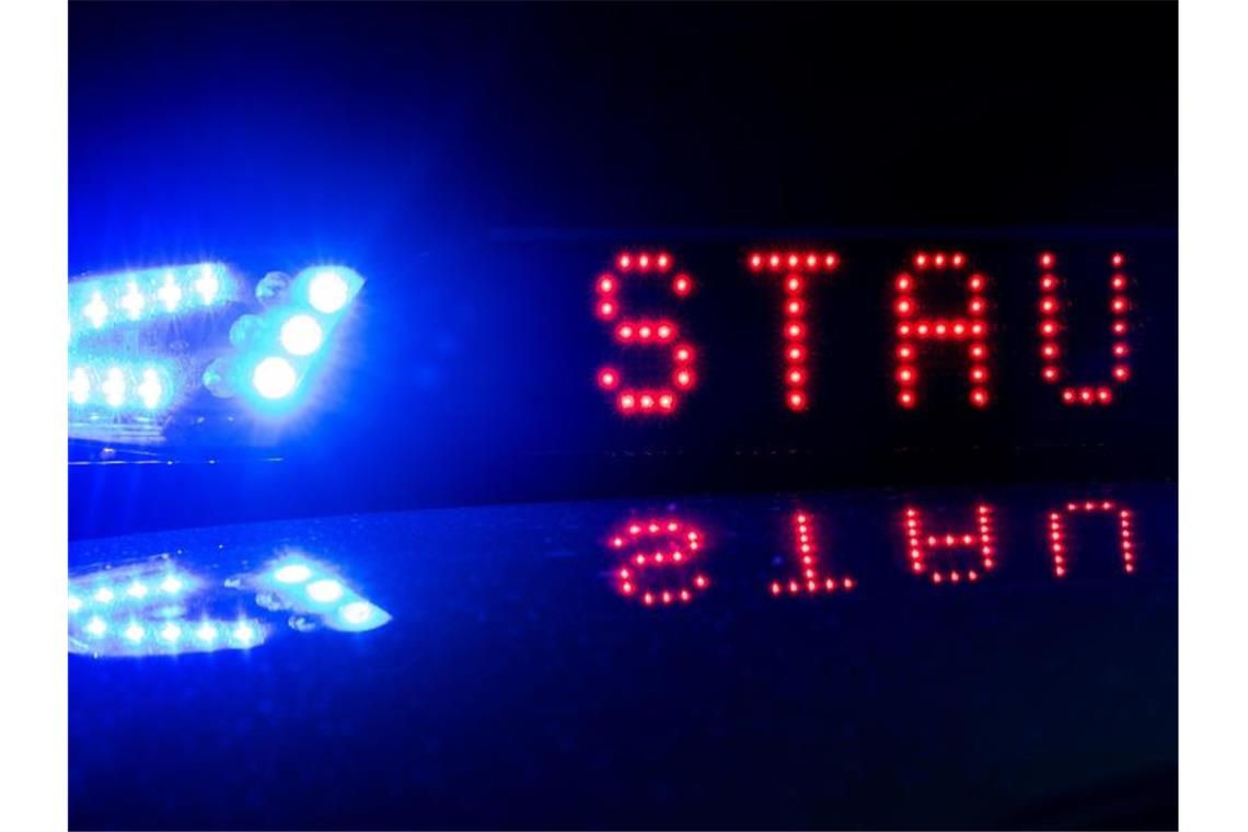 Das Blaulicht auf einem Polizeifahrzeug der leuchtet, während sich das Display mit dem Wort „Stau“ spiegelt. Foto: Monika Skolimowska/zb/dpa/Symbolbild