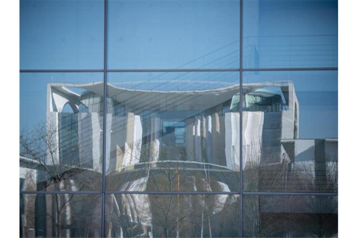 Das Bundeskanzleramt spiegelt sich in der Fassade des Bundestags-Gebäudes, dem Paul-Löbe Haus. Im Kanzleramt beraten Kanzlerin Merkel und die Länderchefs am 17. März in einer virtuellen Konferenz über mögliche Lockerungen der Corona-Maßnahmen. Foto: Michael Kappeler/dpa