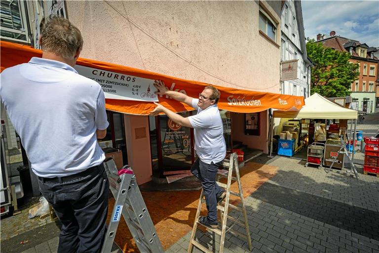 Das Café Weller ist seit der zweiten Auflage des Straßenfests mit dabei. Inhaber David Weller (rechts) widmet sich dem Aufbau des Stands. Foto: Alexander Becher