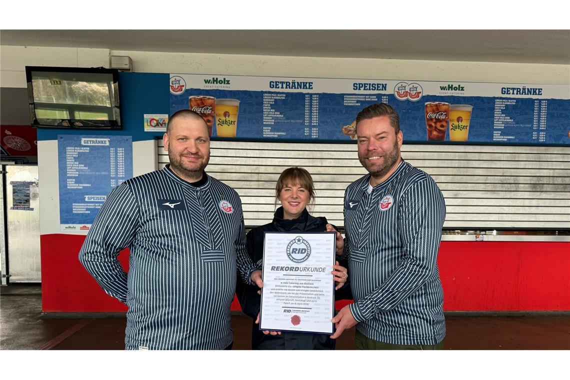 Das Catering-Team des Ostseestadions Rostock um Geschäftsführer Christoph Wulff (r) und Küchenchef Jens Schaumburg (l) hat das längste Fischbrötchen der Welt produziert. Bestätigt wurde der Rekord von Laura Koblischek (M) vom Rekord-Institut Deutschland. (Foto Handout)