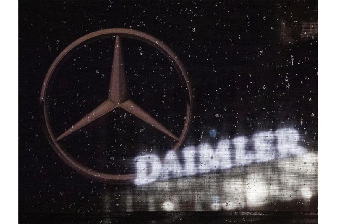Das Daimler-Logo ist an der Konzernzentrale zu sehen, im Vordergrund ist ein Mercedes-Stern abgebildet. Foto: Marijan Murat/dpa/Symbolbild