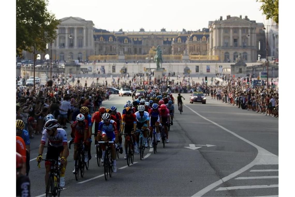 Das Fahrerfeld fährt am Schloss von Versailles vorbei. Foto: Christophe Ena/AP/dpa