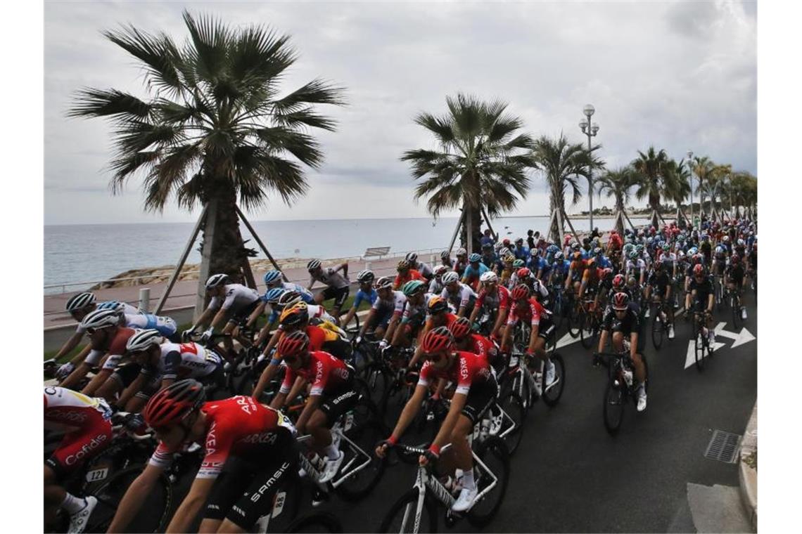 Das Fahrerfeld passiert die Strandpromenade in Nizza. Foto: Christophe Ena/AP/dpa