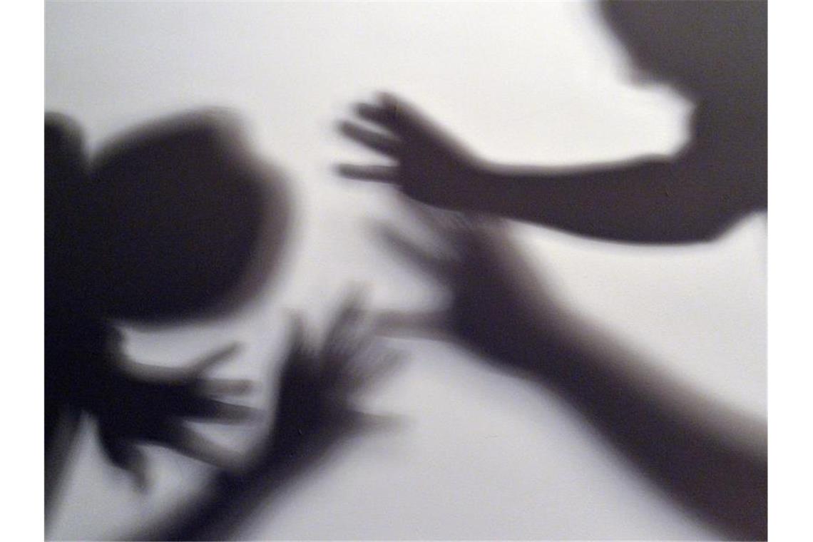 Das gestellte Bild zum Thema häusliche Gewalt symbolisiert, wie ein Kind versucht, sich vor der Gewalt eines Erwachsenen zu schützen. Foto: Maurizio Gambarini/dpa/Symbolbild