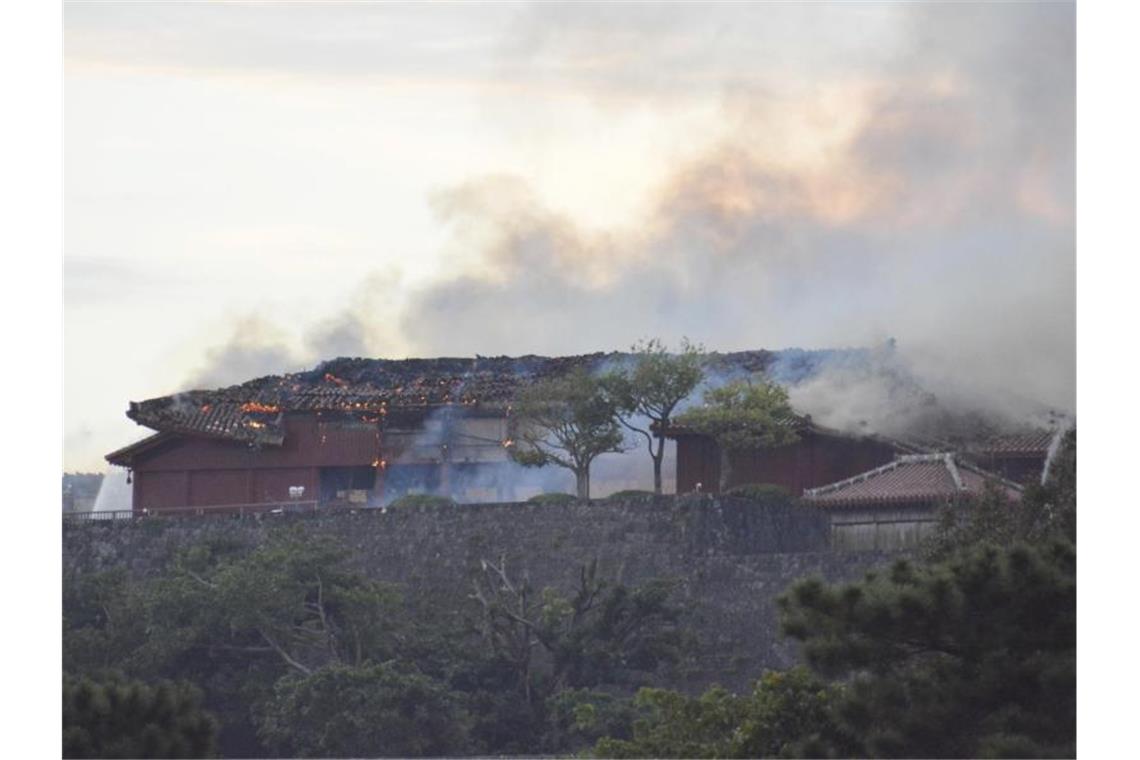 Das Hauptgebäude der Burg qualmt nach dem Brand. Foto: -/kyodo/dpa