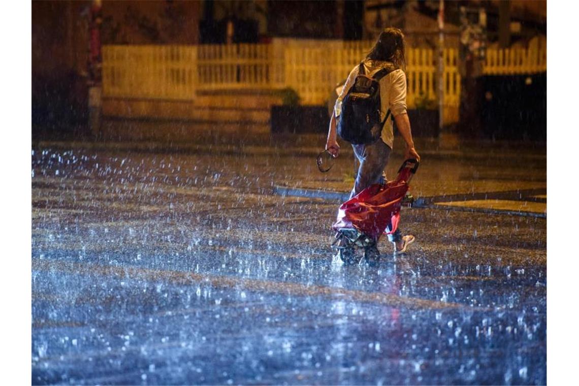 Bis zu 800 Blitze pro Minute - Starkregen flutet den Osten Das heftige Sommergewitter macht diesem Mann in Berlin scheinbar wenig aus. Foto: Gregor Fischer