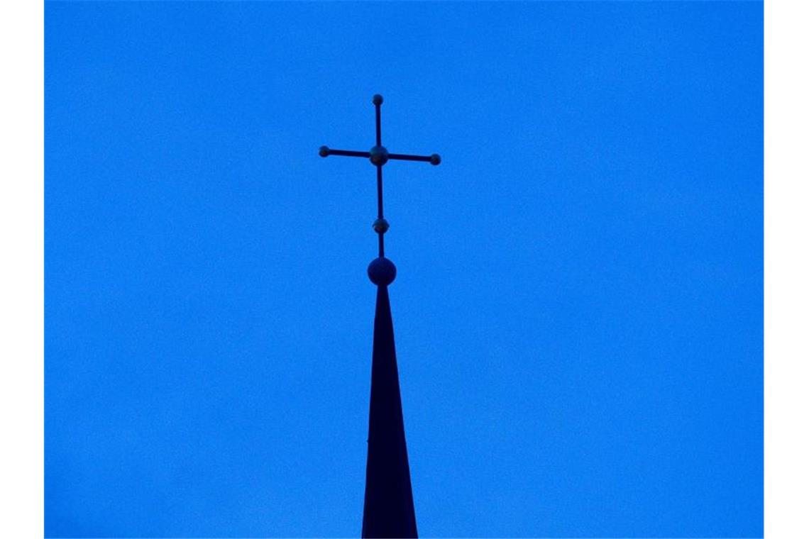 Das Kreuz einer evangelisch-lutherischen Kirche in der Abenddämmerung. Foto: Friso Gentsch/dpa
