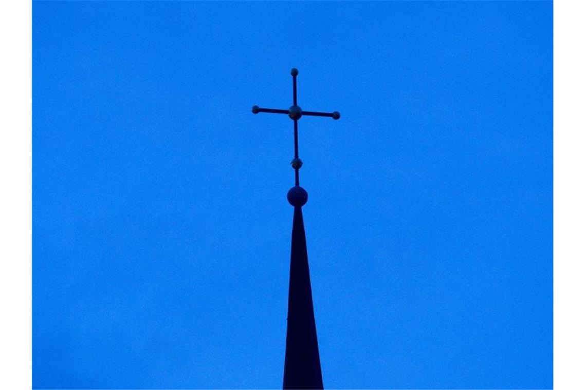 Das Kreuz einer evangelisch-lutherischen Kirche ist in der Abenddämmerung zu sehen. Die Evangelische Kirche in Deutschland zu Weihnachten auch wieder auf Online-Angebote für die Gläubigen. Foto: Friso Gentsch/dpa
