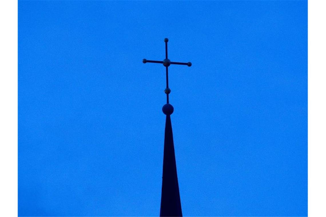 Das Kreuz einer evangelisch-lutherischen Kirche ist in der Abenddämmerung zu sehen. Foto: Friso Gentsch/dpa