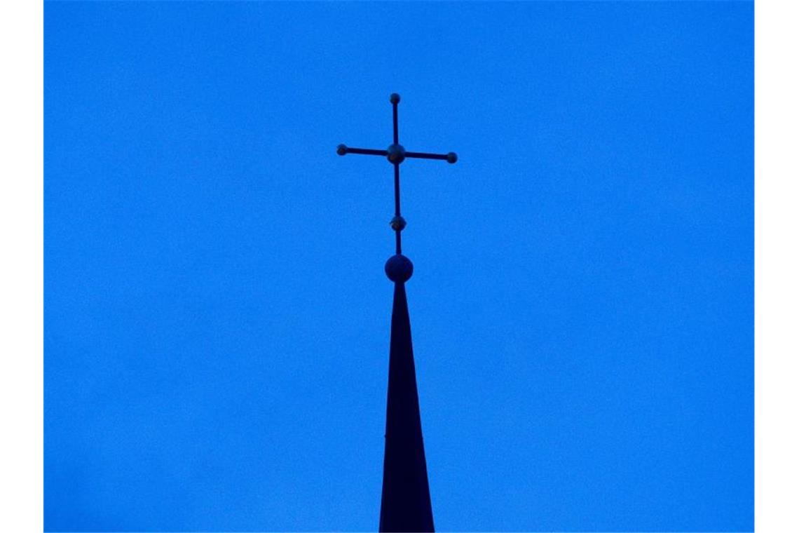 Kirchen-Obere fordern Zusammenhalt im Kampf gegen Klimakrise Das Kreuz einer Kirche ist in der Abenddämmerung zu sehen. Foto: Friso Gentsch/dpa/Symbolbild