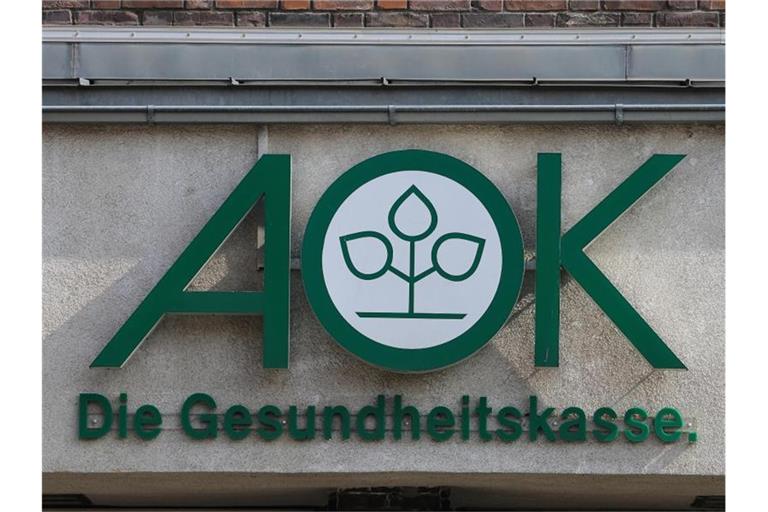Das Logo der AOK ist auf einem Gebäude zu sehen. Foto: Jens Wolf/Archivbild