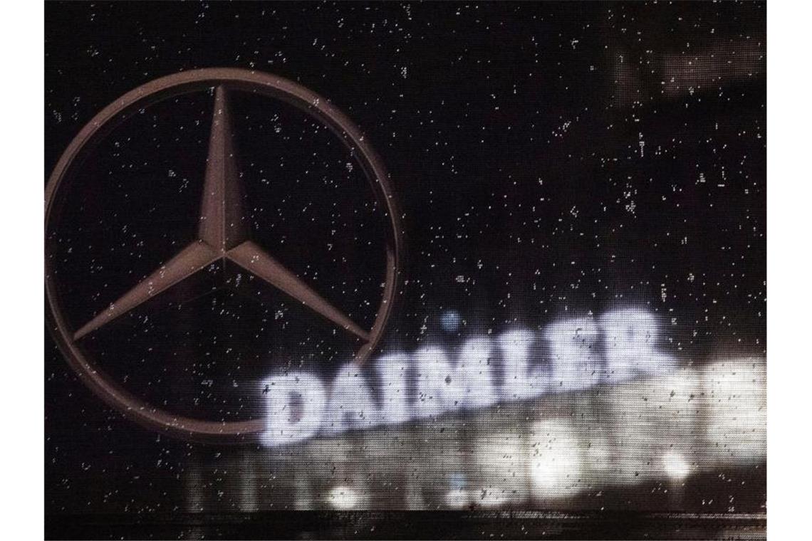Das Logo der Daimler-AG an der Konzernzentrale, gesehen durch eine Fahne mit dem Mercedes-Stern. Foto: Marijan Murat/dpa/Archivbild