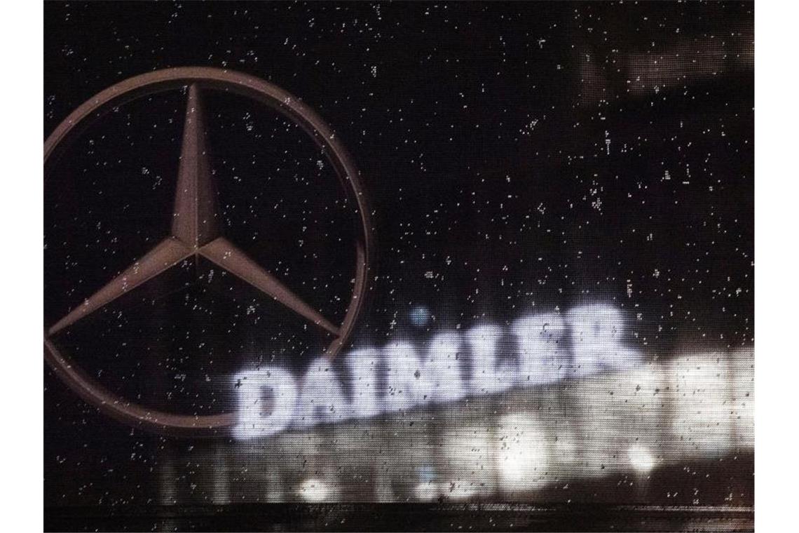 Das Logo der Daimler-AG ist an der Konzernzentrale zu sehen, im Vordergrund ist ein Mercedes-Stern auf einer Flagge abgebildet, die voller Regentropfen ist. Foto: Marijan Murat/dpa/Archiv