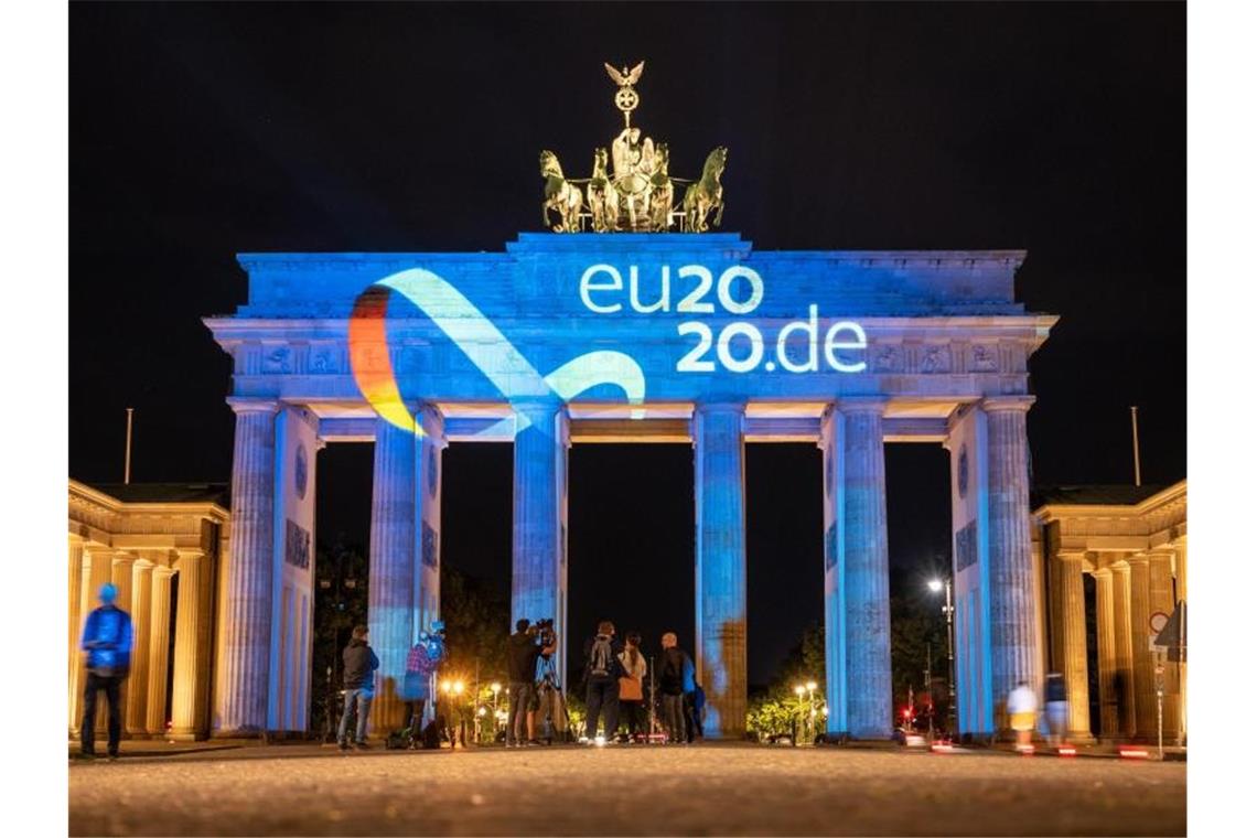 Das Logo der deutschen Ratspräsidentschaft wird auf das Brandenburger Tor in Berlin projiziert. Foto: Christophe Gateau/dpa