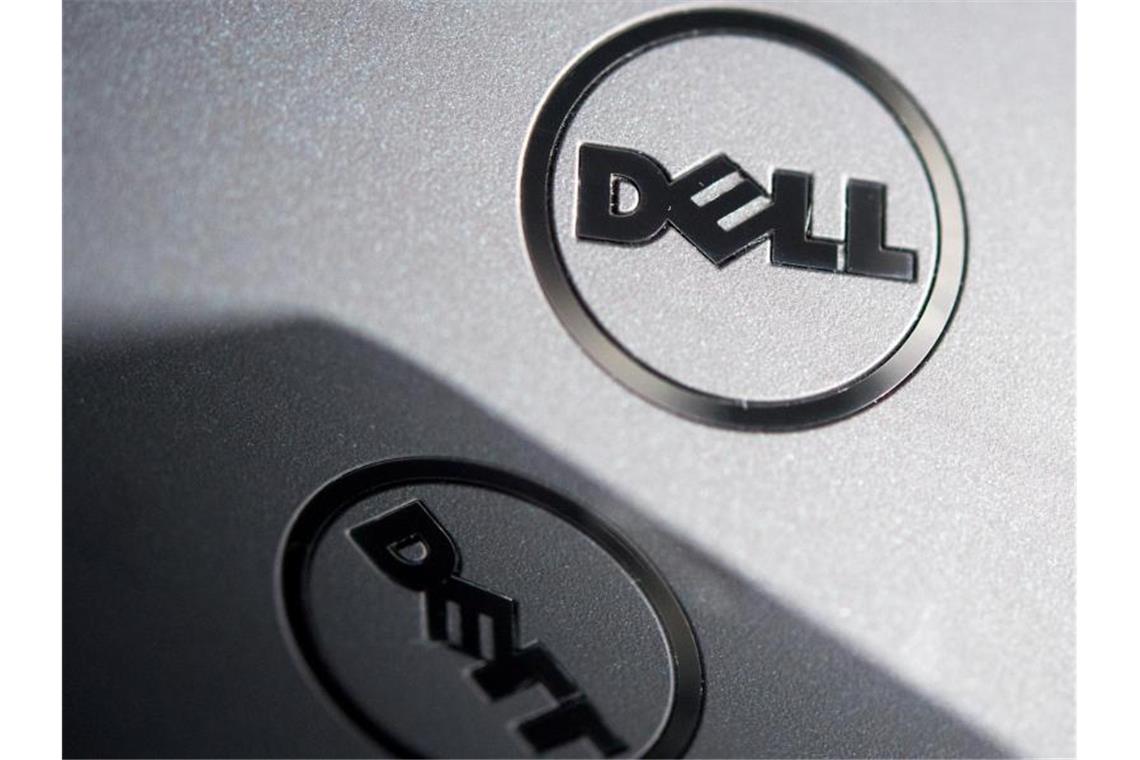 Das Logo der Firma Dell auf dem Gehäuse eines Laptops spiegelt sich im Bildschirm eines Smartphones. Foto: Monika Skolimowska/ZB/dpa