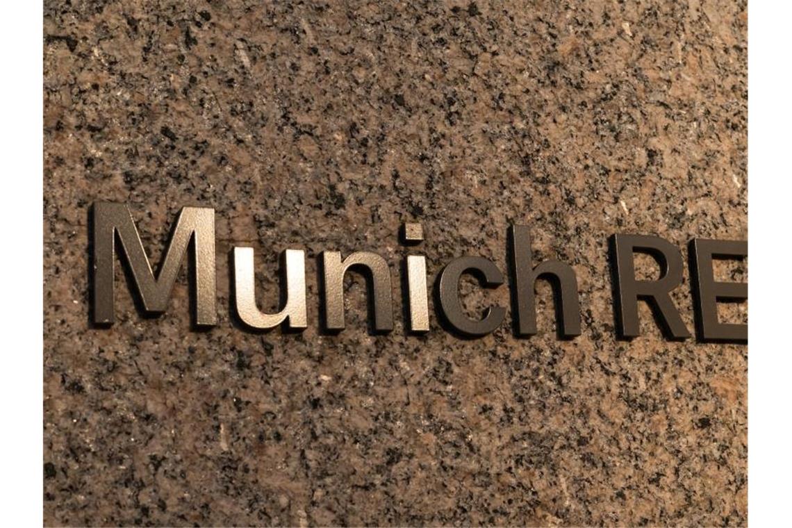 Das Logo der Munich RE klebt an der Mauer vor dem Haupteingang des Verwaltungsgebäudes der Münchener Rückversicherungs-Gesellschaft AG (Munich Re) im Münchner Stadtteil Schwabing. Foto: Peter Kneffel/dpa