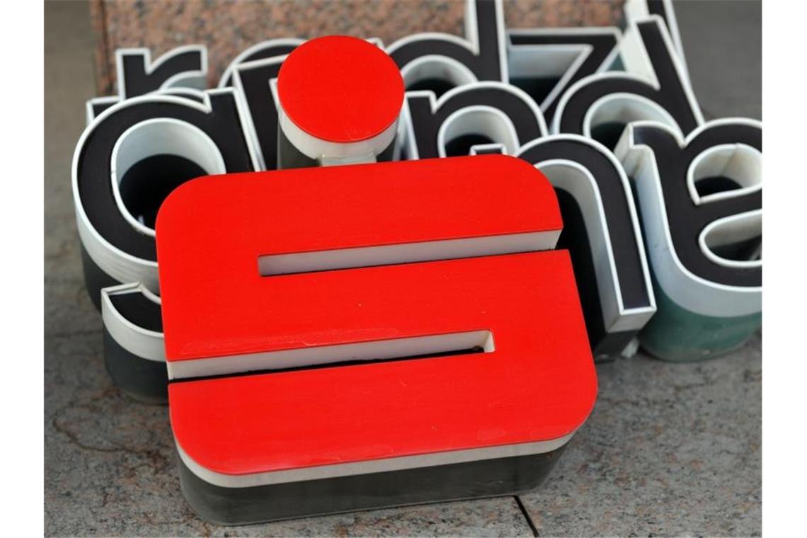 Das Logo der Sparkasse liegt während der Reinigung vor einer Bankfiliale. Foto: Peter Kneffel/dpa/Archivbild/Illustration