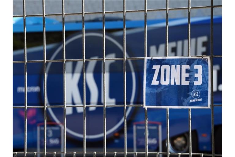 Das Logo des KSC ist hinter einem verschlossenen Tor zu sehen. Foto: Matthias Hangst/Getty Images Europe/Pool/dpa/Archivbild