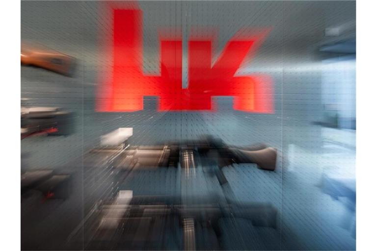 Das Logo des Waffenherstellers Heckler & Koch ist auf dem Firmengelände an einer Präsentationswand neben Waffen zu sehen. Foto: Marijan Murat/dpa/Symbolbild