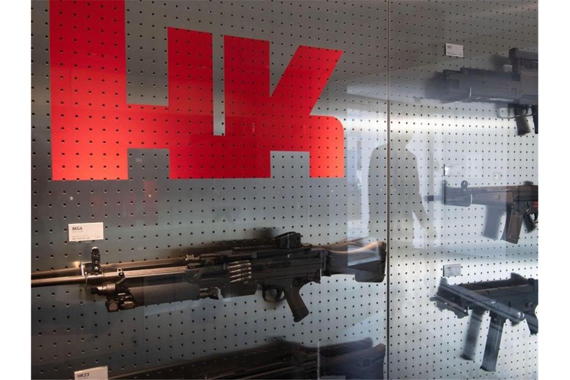 Das Logo des Waffenherstellers Heckler & Koch ist auf dem Firmengelände an einer Präsentationswand neben Waffen zu sehen. Foto: Marijan Murat/dpa