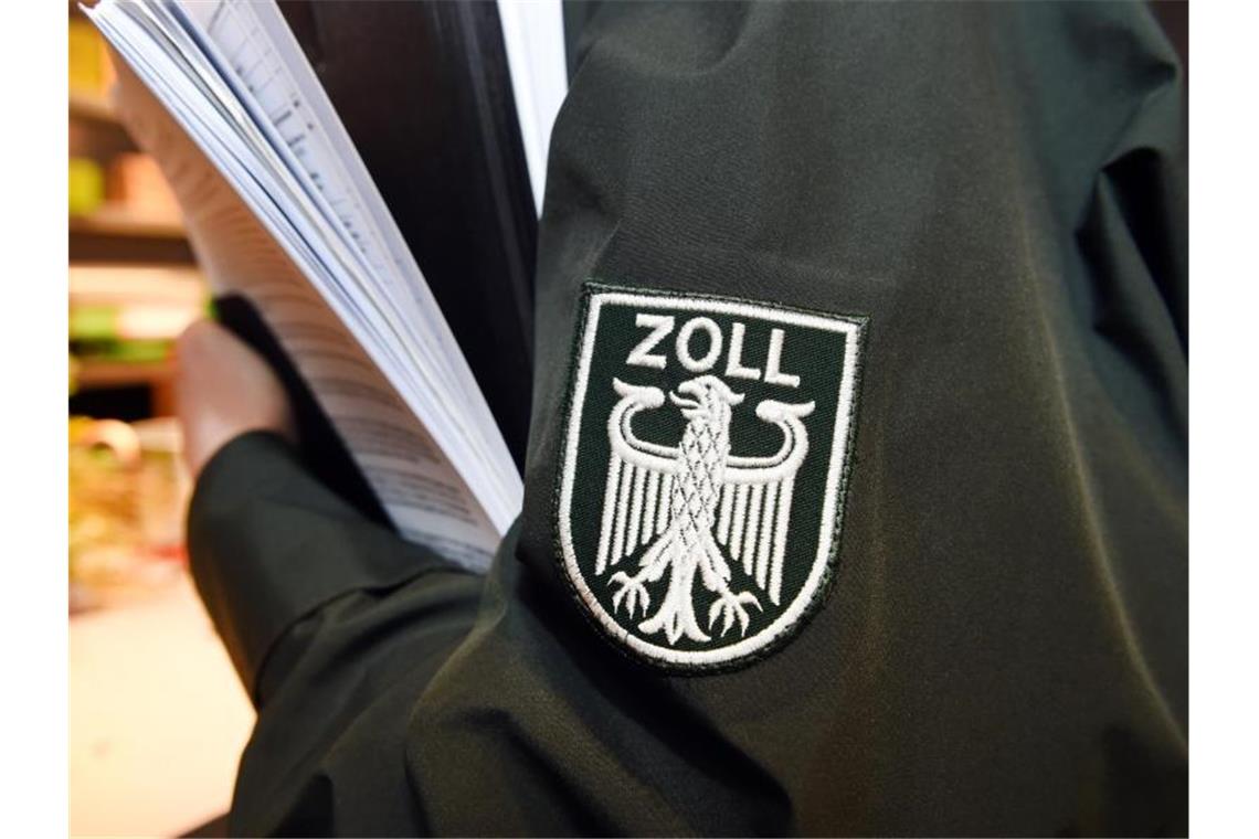 Das Logo des Zolls ist auf der Jacke eines Zollbeamten zu sehen. Foto: Stefan Sauer/Archvibild